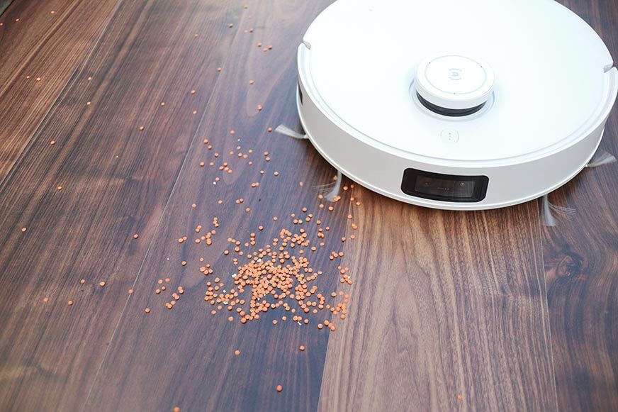 Ecovacs Deebot T10 reinigt Linsen auf einem Laminatboden im Saugtest.